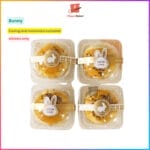 Four mooncakes with bunny stickers and packaging